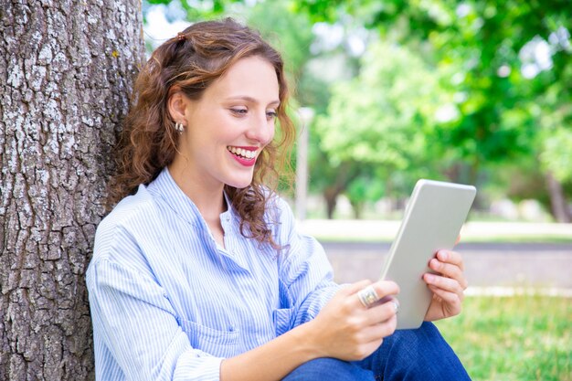 Feliz joven hablando a través de la aplicación de telecomunicaciones en tableta