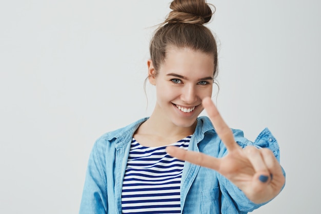 Foto gratuita feliz joven haciendo gesto de victoria con los dedos, signo v