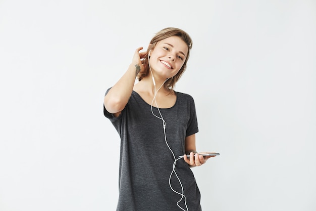 Feliz joven hermosa chica en auriculares con teléfono sonriendo.