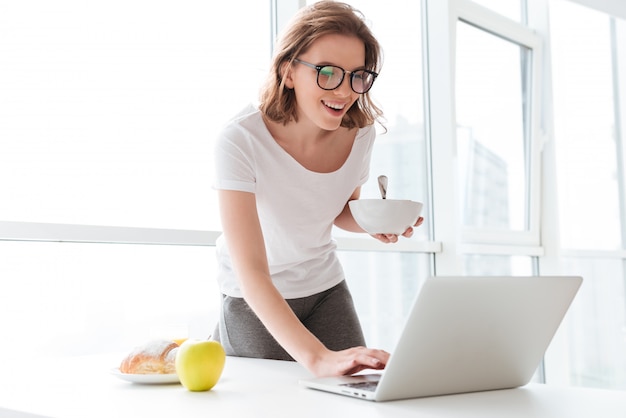 Feliz joven increíble mujer escribiendo por computadora portátil.