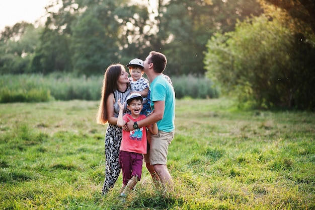 Feliz joven madre de familia padre dos hijos hijo en la naturaleza divirtiéndose