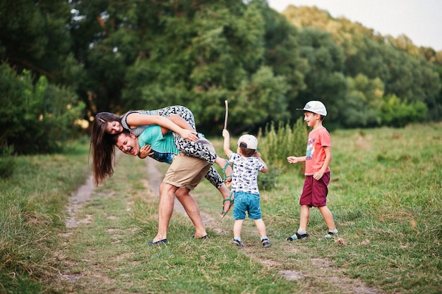 Feliz joven madre de familia padre dos hijos hijo en la naturaleza divirtiéndose