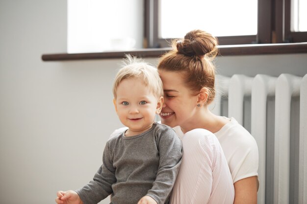 Feliz joven madre con hijo pequeño en casa