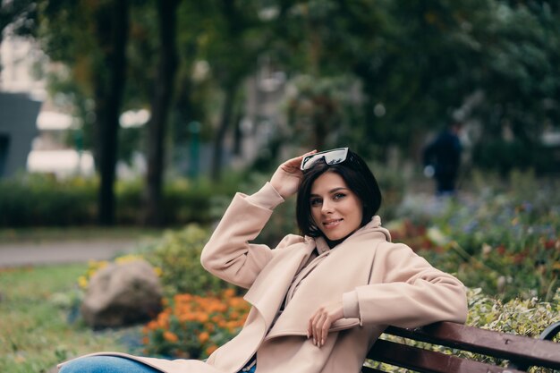 Feliz joven morena sentada en un banco del parque