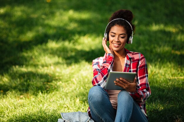 Feliz joven mujer africana sentada al aire libre en el parque.