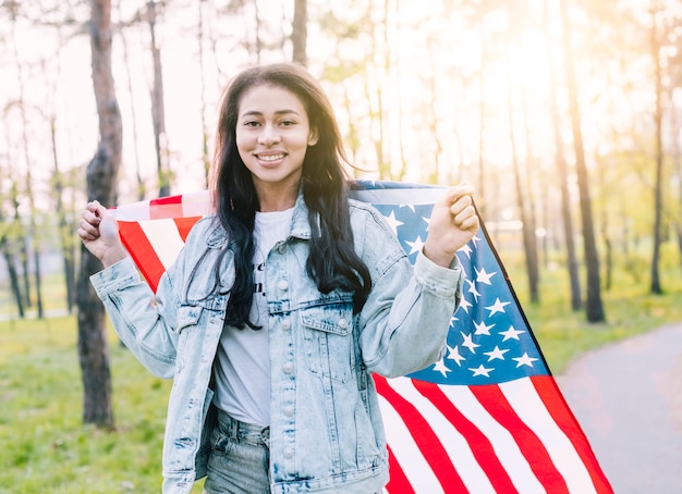 Feliz joven mujer étnica con bandera americana