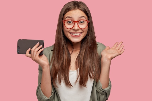 Feliz joven mujer con mirada atractiva, emociones positivas, agarra las manos, tiene una amplia sonrisa