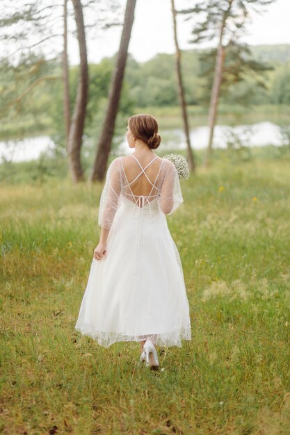 Feliz joven novia en un vestido de novia blanco bosque de pinos