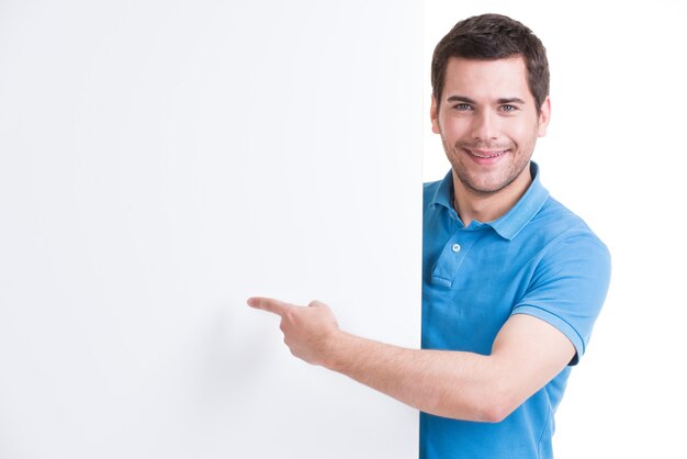 Foto gratuita feliz joven señala con el dedo en una pancarta en blanco - aislado en blanco.