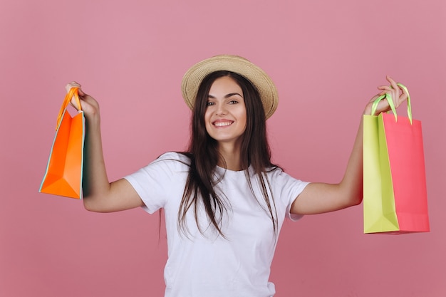 Feliz joven en un sombrero posa con coloridos bolsos de compras