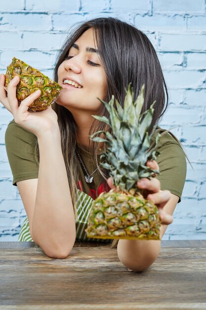 Feliz joven sosteniendo piña sobre superficie azul