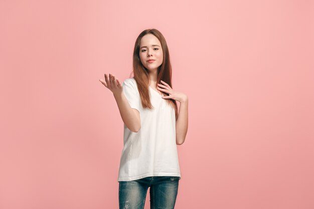 Feliz jovencita de pie, sonriendo aislado en estudio rosa de moda