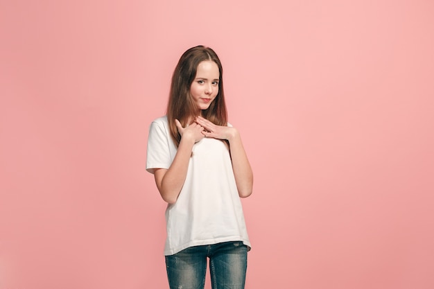 Feliz jovencita de pie, sonriendo aislado en estudio rosa de moda