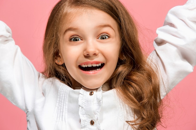 Feliz jovencita de pie, sonriendo aislado en estudio rosa de moda