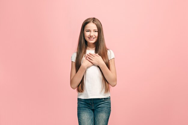 Feliz jovencita de pie, sonriendo aislado en estudio rosa de moda