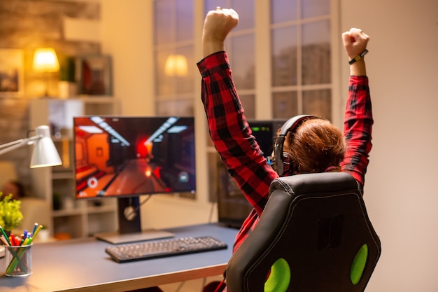 Feliz jugador emocionado ganando un videojuego en línea a altas horas de la noche en la sala de estar