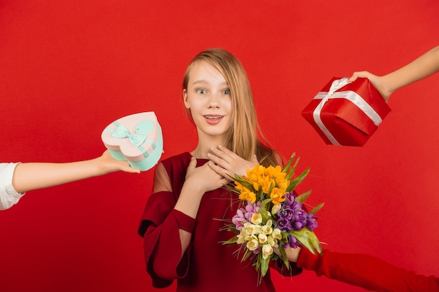 Feliz, linda chica caucásica aislada en estudio rojo