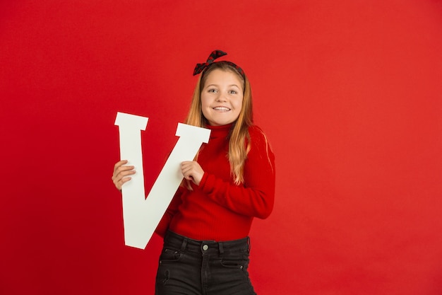 Feliz, linda chica caucásica con letra en estudio rojo