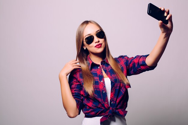 Feliz linda mujer haciendo selfie aislado sobre pared gris.