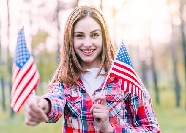 Feliz linda mujer joven con banderas americanas