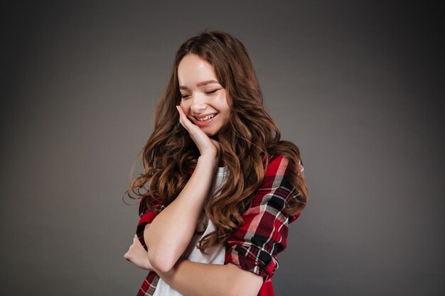 Feliz linda mujer joven en camisa a cuadros de pie y riendo