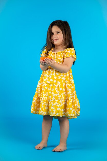 Feliz linda niña ropa de bebé amarilla de moda posando estudio sobre fondo azul