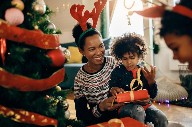 Feliz madre afroamericana divirtiéndose con sus hijos el día de Navidad en casa