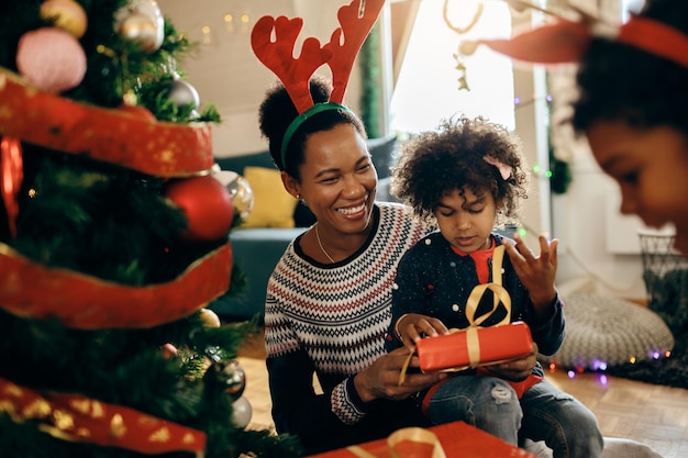 Feliz madre afroamericana divirtiéndose con sus hijos el día de Navidad en casa