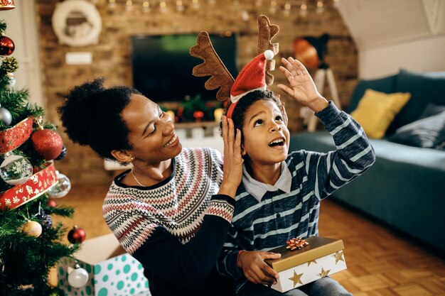 Feliz madre afroamericana e hijo divirtiéndose el día de navidad en casa