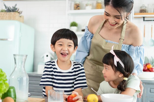 Feliz madre asiática con hijo e hija en la cocina Disfrute de la actividad familiar juntos