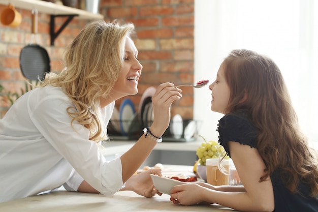 Feliz madre e hija desayunando en la cocina