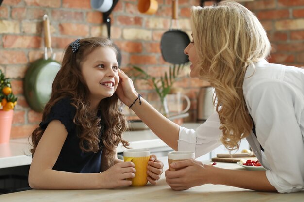 Feliz madre e hija desayunando en la cocina