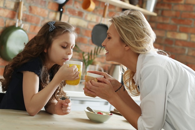 Feliz madre e hija desayunando en la cocina