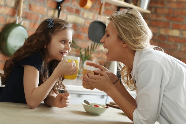 Feliz madre e hija desayunando en la cocina