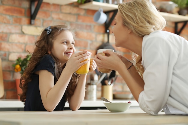 Feliz madre e hija desayunando en la cocina