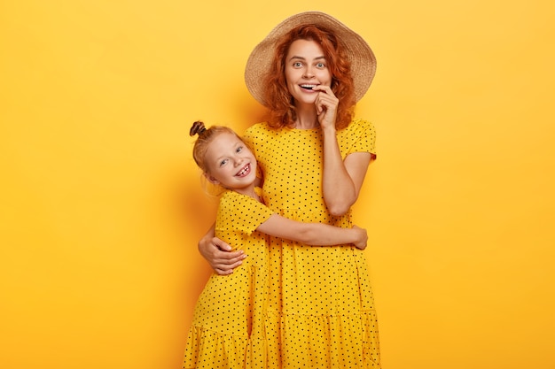 Foto gratuita feliz madre e hija pelirroja posando en vestidos similares