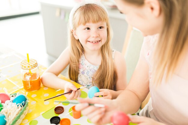 Feliz madre e hija pintando huevos