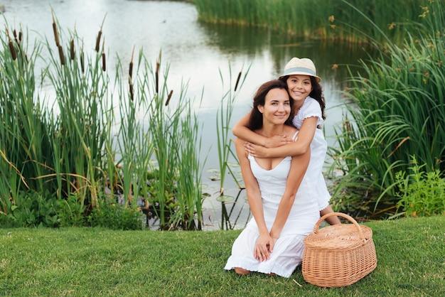 Feliz madre e hija posando junto al lago