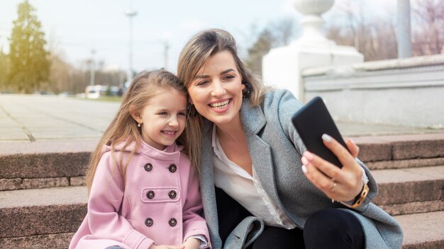 Feliz madre e hija tomando selfie al aire libre