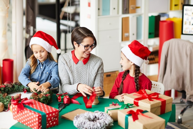 Feliz madre e hijas envolver regalos de Navidad