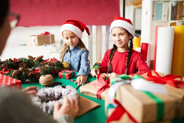 Feliz madre e hijas envolver regalos de Navidad