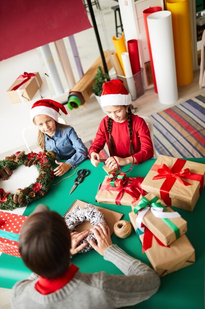 Feliz madre e hijas envolver regalos de Navidad