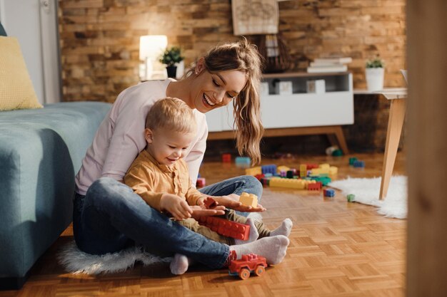 Feliz madre e hijo jugando con bloques de juguete en la sala de estar