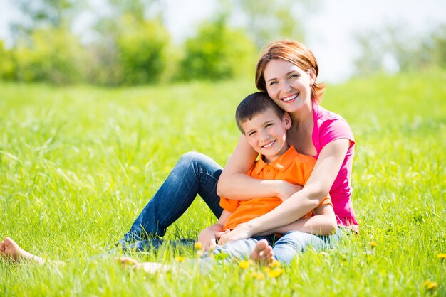 Feliz madre e hijo en el retrato al aire libre de la pradera de primavera