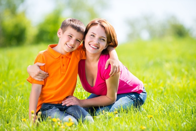 Feliz madre e hijo en el retrato al aire libre de la pradera de primavera