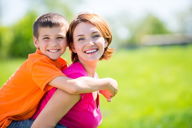 Feliz madre e hijo en el retrato al aire libre de la pradera de primavera