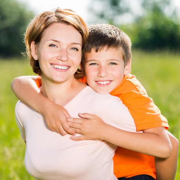 Feliz madre e hijo en el retrato al aire libre de la pradera de primavera