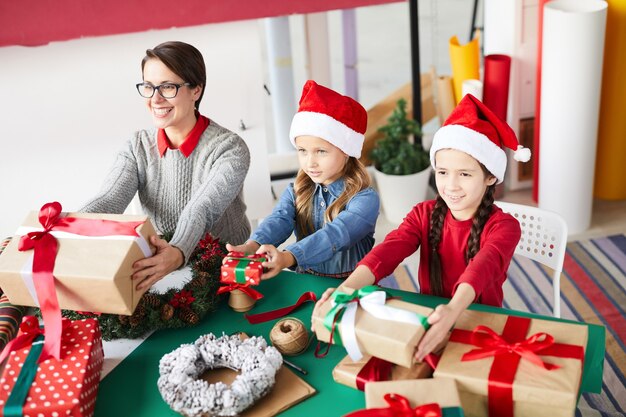 Feliz madre e hijos intercambiando regalos de Navidad