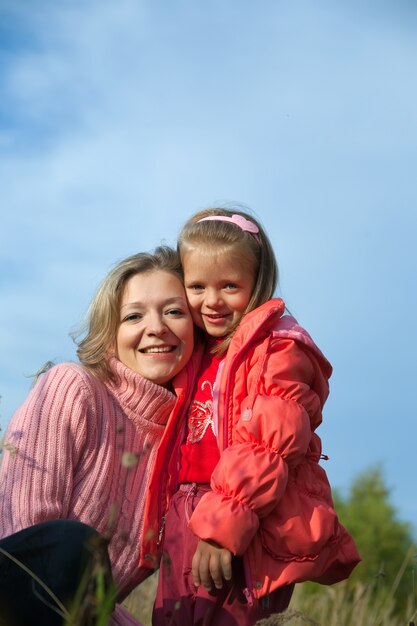 Feliz madre con la hija contra el cielo