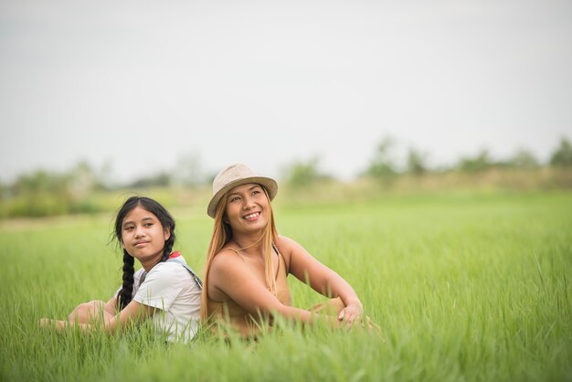 Feliz madre con hija sentada en el parque de campo de hierba